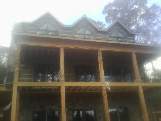 Dormers and porch framing on a large log home under construction — Roof Coating work by our crew in Fort Washington