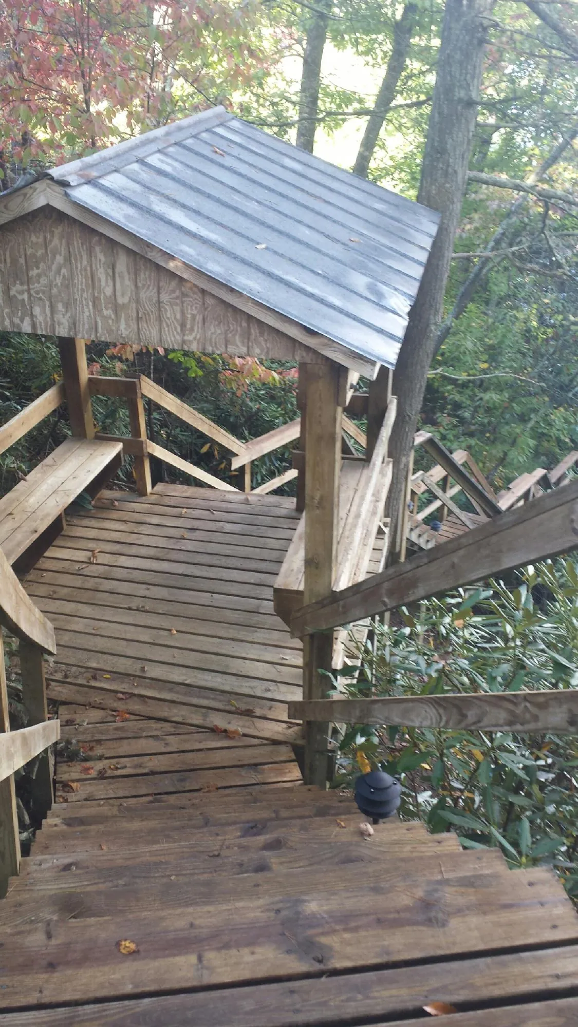 Metal roofed shelter over wooden steps on a wooded walkway — Skylight Repair & Installation work by our crew in Fort Washington